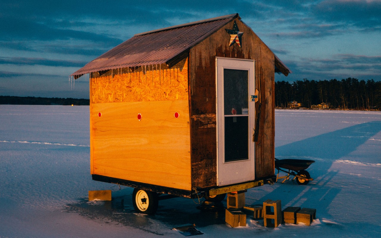 An ice-fishing hut on a frozen lake at dusk