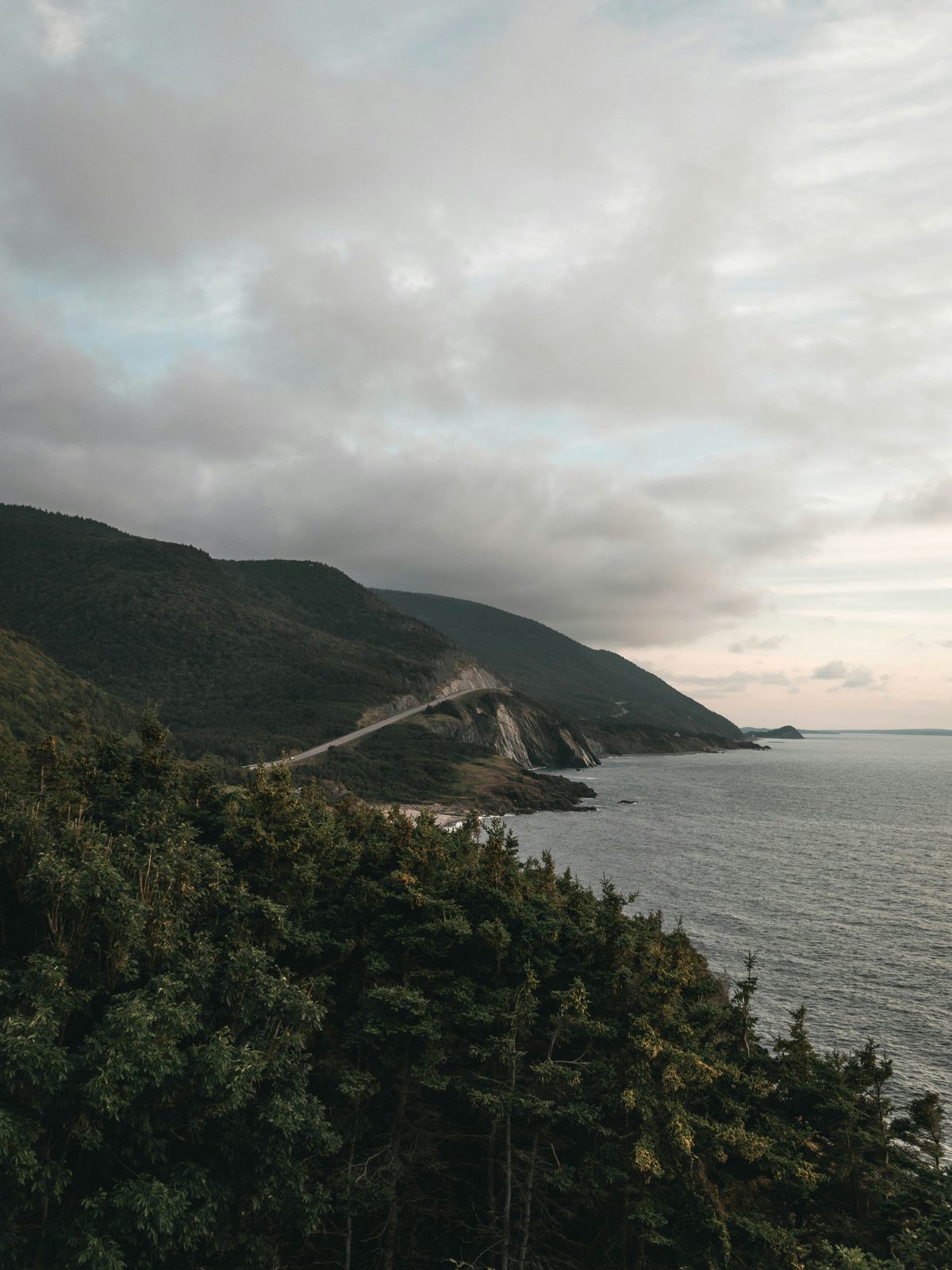 The Cabot Trail winding along a forested headland above the sea in Cape Breton
