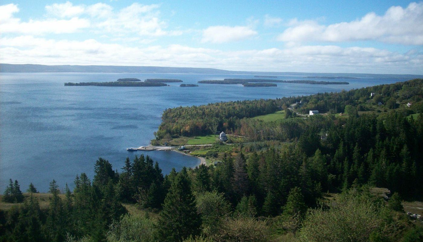 Wooded islands and a wide blue bay seen from a hillside on Bras d’Or Lake
