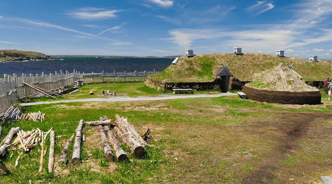 Reconstructed sod-covered Norse buildings behind a wooden fence at L’Anse aux Meadows