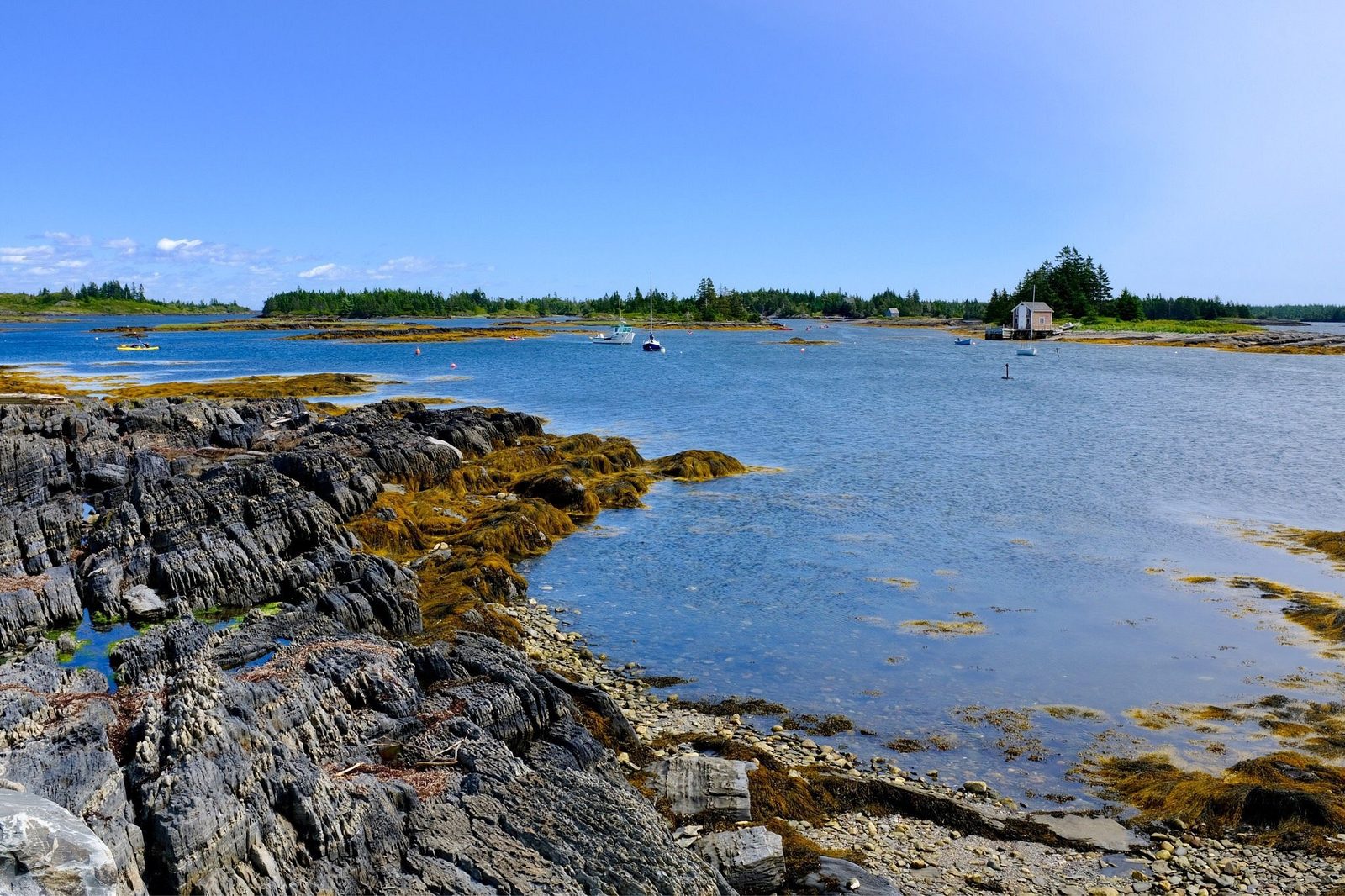 A rocky shore and calm blue bay with small islands on Nova Scotia’s South Shore