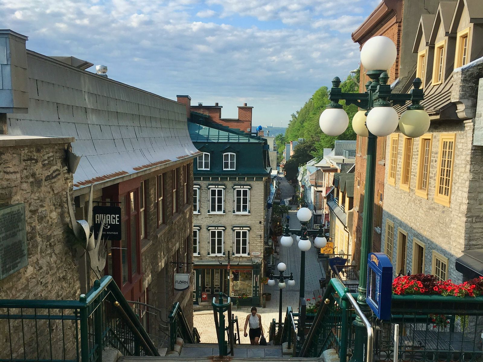A stairway between old stone buildings in Quebec City with lamp posts and flower boxes