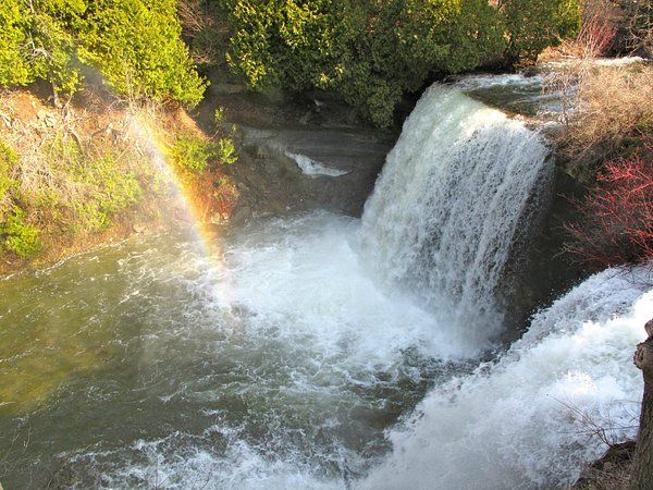 A waterfall plunging into a rocky gorge with a rainbow in the spray