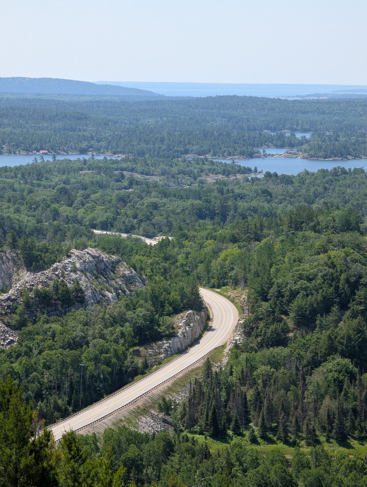 A road winding through forest and lakes seen from above