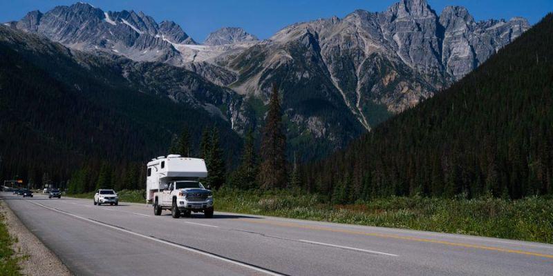 A truck camper driving along a mountain highway in the Canadian Rockies