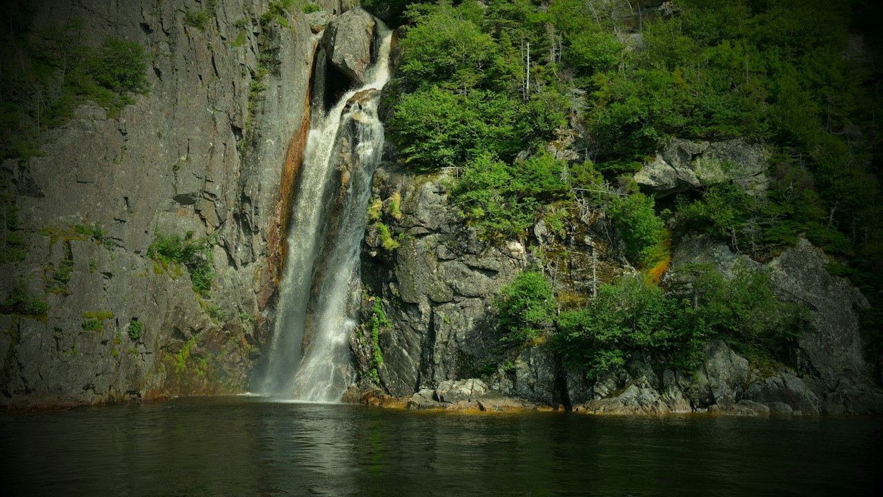 A waterfall plunging down a rock face beside Western Brook Pond in Gros Morne National Park, on the Viking Trail route