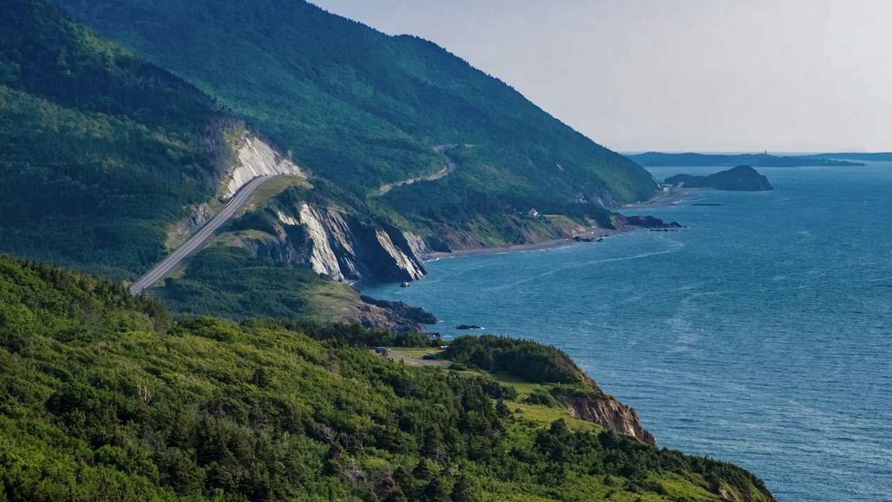 The Cabot Trail winding along green cliffs above the Gulf of St. Lawrence in Cape Breton Highlands